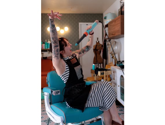 Stylist striking a fun pose with a curling wand at Curl Up and Dye Salon in Flagstaff, AZ