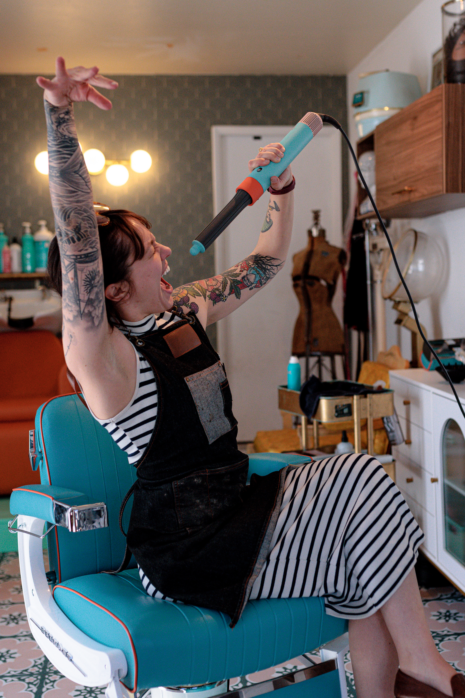 Stylist striking a fun pose with a curling wand at Curl Up and Dye Salon in Flagstaff, AZ