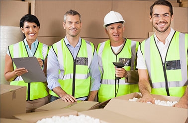 Four people in high visibility construction vests standing with boxes.