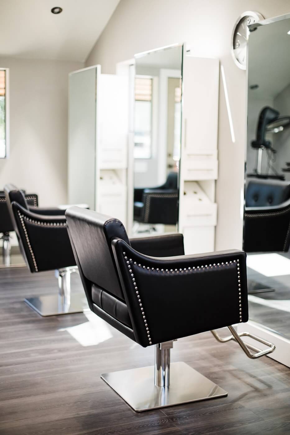 Side view of black upholstered styling chairs at Paige Lynn Beauty.